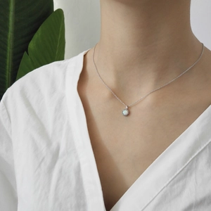 Detail of s925 sterling silver necklace featuring a round white opal pendant on a model