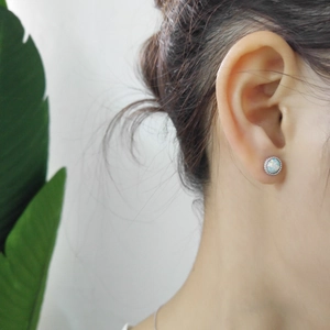Close-up of minimalist S925 sterling silver opal stud earrings worn on a female ear