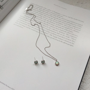 Detail of S925 silver opal jewelry set including necklace and earrings on a book