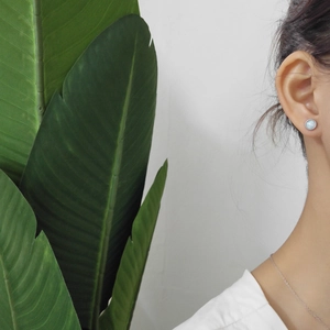 Close-up of S925 sterling silver opal pendant necklace worn by a model with green leaf