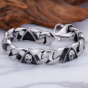 Gothic punk pharaoh skull men's stainless steel bracelet on a marble and wood backdrop