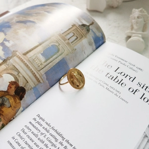 Detailed macro of golden oval religious medallion ring with intricate relief on art book