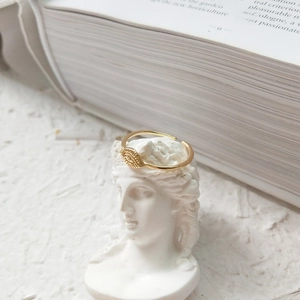 Artistic display of a gold evil eye open ring on a white plaster statue head detail