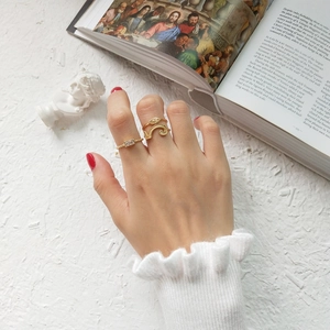 Detail of vintage gold stackable rings with wavy texture and emerald cut zircon on hand