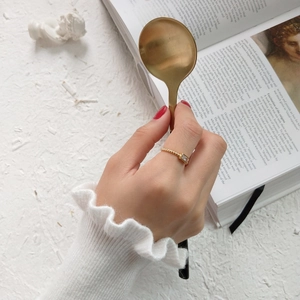 Detailed shot of a gold twist rope ring with a rectangular crystal on a model's hand