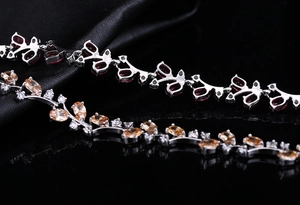 Detail of floral bracelets with red and champagne stones on a premium black leather background
