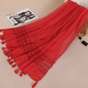 Detail of red scarf showing intricate lace embroidery and long fringe tassels at the edge
