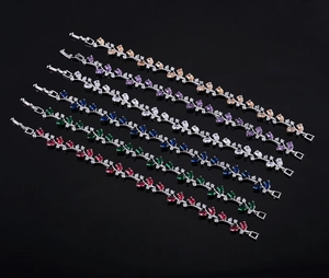 Detail showing various colors of leaf-shaped zircon bracelets on a black background