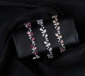 Detailed macro view of leaf shaped 18K white gold bracelets with red and champagne crystals