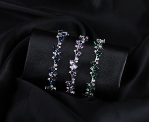 Detail of elegant vine-leaf bracelets with blue, purple, and green pear-cut gemstones
