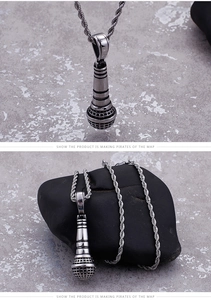 Detailed view of silver microphone pendant with twisted rope chain on stone background