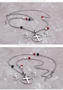 Detail of cross and ring pendant set with red, black, and white beads on a grey stone texture