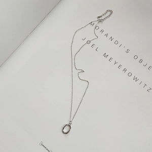 Macro detail of S925 sterling silver irregular oval pendant necklace on art book