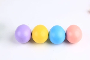 Vue détaillée de quatre œufs de Pâques en bois colorés en violet, jaune, bleu et rose