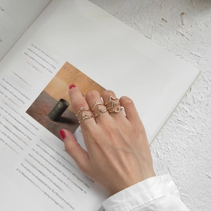 Close-up of gold geometric rhinestone rings worn by a model in a refined lifestyle setting
