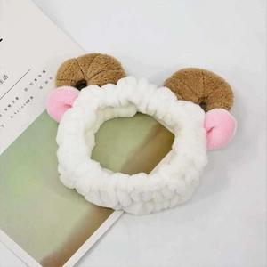 Detail of white plush sheep ear headband with brown horns on a book background