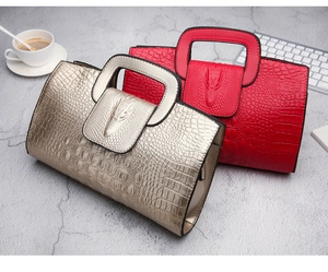 Detail of crocodile pattern embossed handbags in gold and red with 3D crocodile head motif