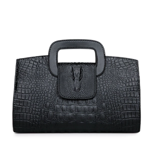 Bolso negro con textura de cocodrilo, cierre de cabeza animal y asa recortada elegante