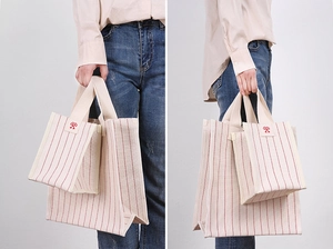 Detail of red striped canvas tote bag showing side and front view with square logo patch
