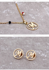 Detail eines goldenen M-Schmucksets mit farbigen Perlen auf grauem Steinuntergrund
