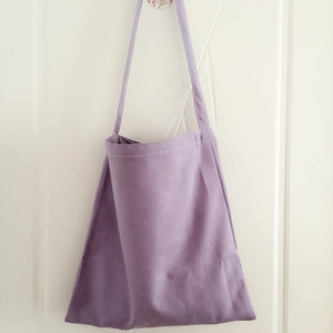 Detail view of solid lavender canvas tote bag hanging on a door in minimalist style