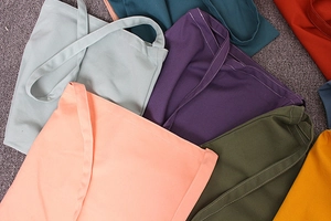 Flat lay of colorful solid canvas tote bags showing multiple shades and durable stitching