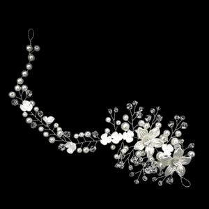 Detail showing white flowers and crystal pearls on a bridal hair vine over a black background