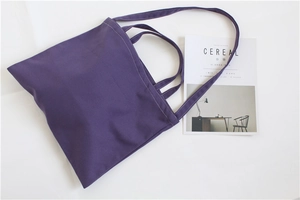 Detail of purple canvas tote bag with dual handles and long shoulder strap in minimalist style