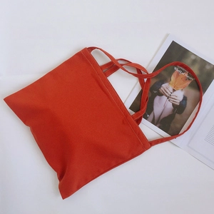 Detail shot of a bright red canvas tote bag with clean stitching and dual top handles