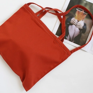 Detail of red canvas tote bag with reinforced white stitching and textile shoulder strap
