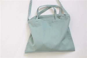 Detail of mint green canvas tote bag with dual handles and a fixed shoulder strap