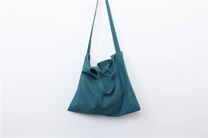 Detail of green canvas tote bag featuring reinforced stitching and minimalist handle
