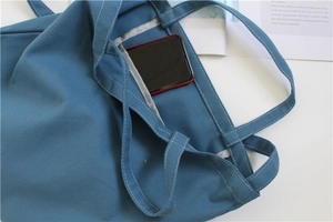 Close-up of blue canvas tote bag interior showing the inner pocket with a smartphone