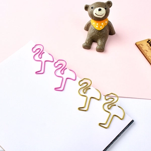 Trombones en forme de flamant rose et doré sur un carnet blanc avec fond de couleur pastel