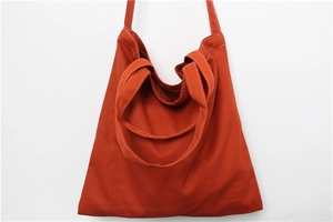 Detail showing the burnt orange canvas tote bag with contrast white stitching and wide strap