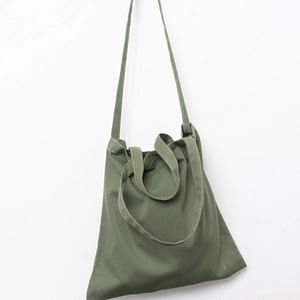 Detail of dark green canvas tote bag showing durable texture and white stitching details