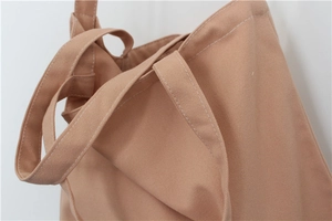 Detailed close-up of double stitching and thick canvas texture on brown tote bag