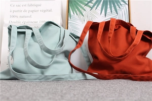 Detail of light blue and brick red canvas tote bags with durable double shoulder straps