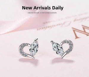 Close-up of heart-shaped silver earrings with marquise-cut stone on silk background