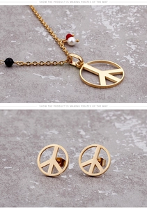 Macro detail of gold titanium steel peace sign necklace and stud earrings set
