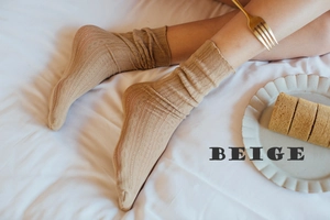 Macro shot of beige hollow cable knit socks with ruffled edges in a cozy home setting