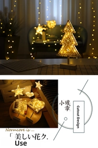 Detail of warm LED night light with metal hollow tree, star, and heart shapes on wood base