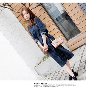 Detail of a navy blue polka dot dress featuring a belted waist and long sleeves