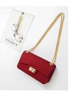 Detail view of dark red crossbody bag with V-quilted texture and gold chain strap