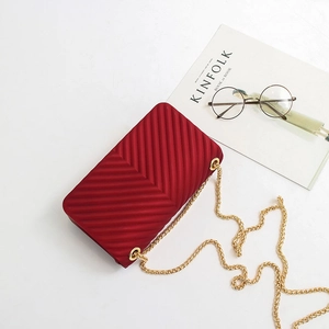 Red V-patterned chain bag with a matte finish shown in a flat lay minimalist setting