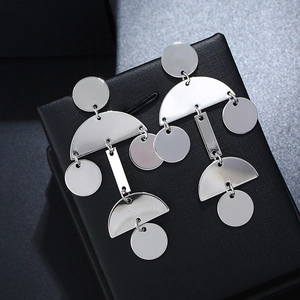 Macro shot of silver geometric tiered earrings on a black textured jewelry box cover