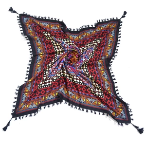 Flat lay of bohemian square scarf featuring colorful geometric patterns and black tassels