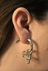 Macro detail of silver gothic skeleton bone earring showing texture and metal finish