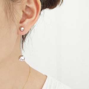 Close-up of elegant long silver tassel earrings with round metal balls on a female model