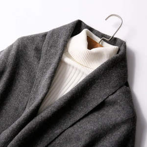 Thick dark grey wool scarf displayed on a wooden hanger with a white sweater